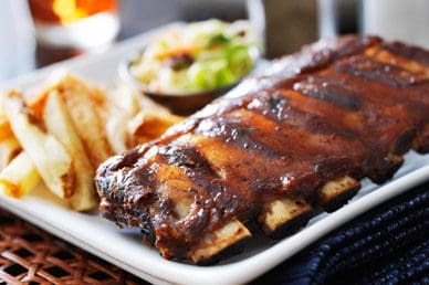 A plate of ribs and fries on the table.