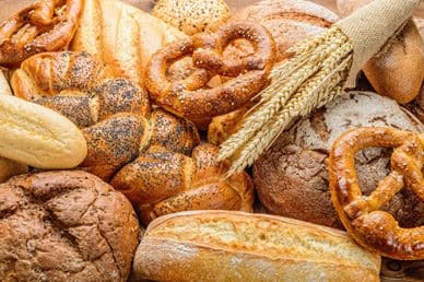 A variety of breads and pretzels are on the table.