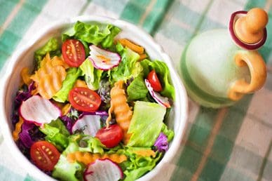 A bowl of salad with tomatoes, lettuce and carrots.