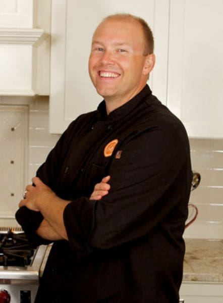 A man standing in front of an oven with his arms crossed.