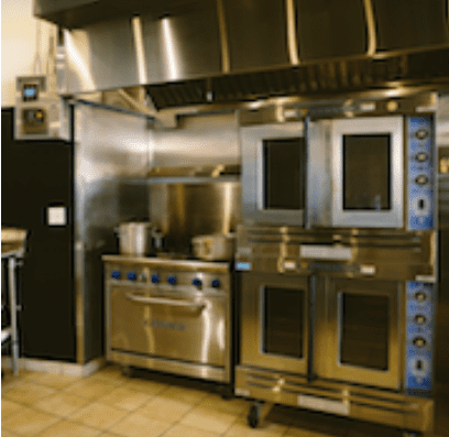 A kitchen with three ovens and a stove.