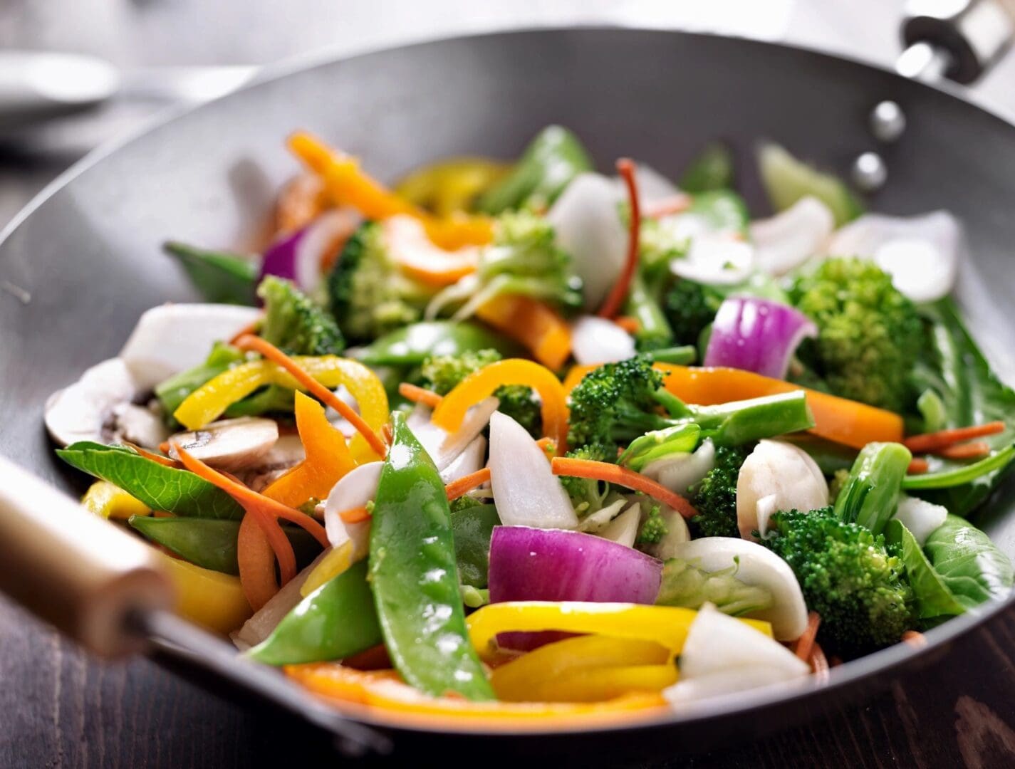 A wok filled with vegetables and meat on top of a table.