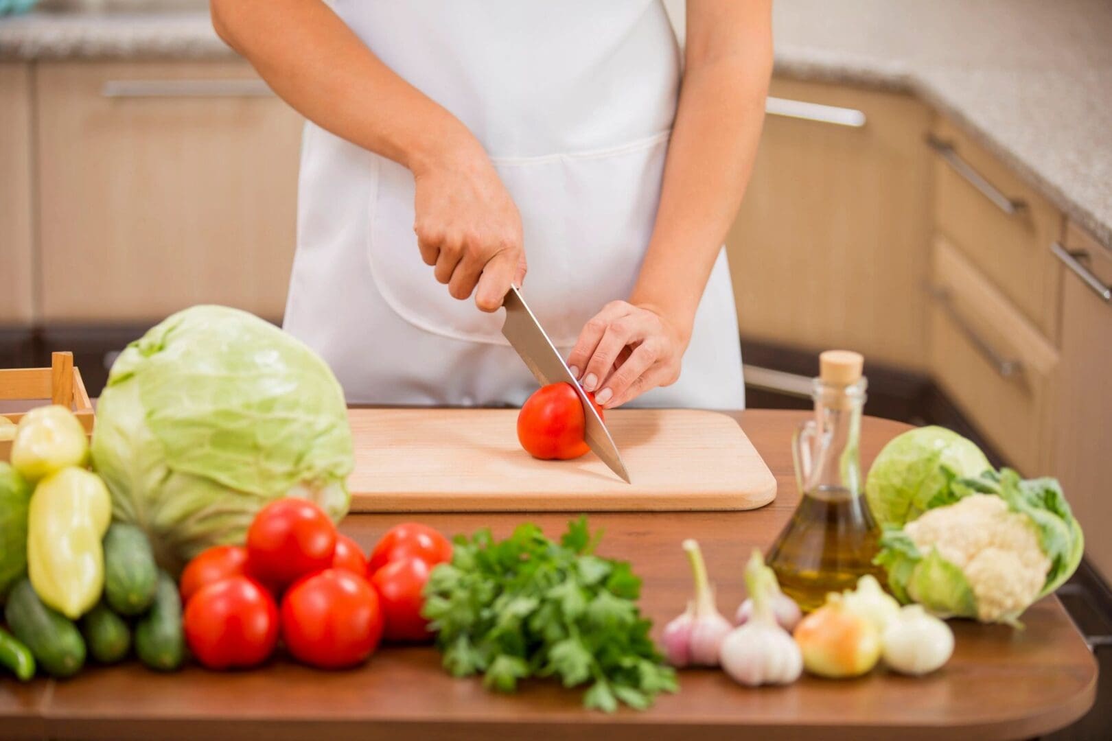 A person cutting tomatoes on top of a wooden table.