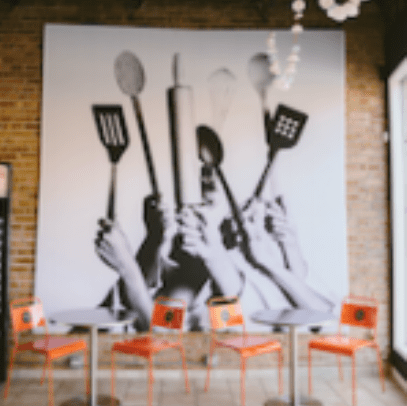 A large picture of people holding utensils in the middle of a room.